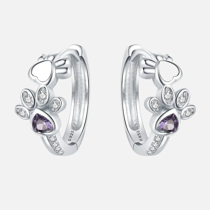 Oorbellen met pootafdruk in zilver met zirkonia en een hartvormige edelsteen.